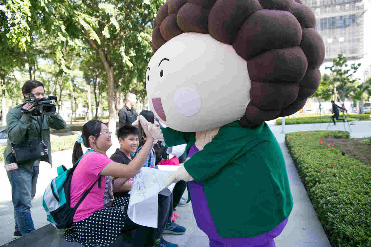 花媽人偶帶著高雄市2018特色年曆，在總圖前快閃發放。 圖：高雄市政府/提供