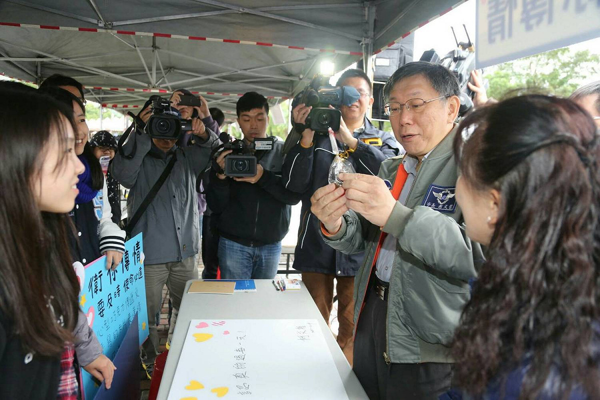柯文哲後來開始逛校園攤位，經過「巧克力傳情」攤位時，立刻遭學生慫恿傳情給陳佩琪，他笑笑回應「太肉麻了，我簽名就好」，最後僅在卡片上寫下「快樂的過每一天」。 圖：台北市政府提供