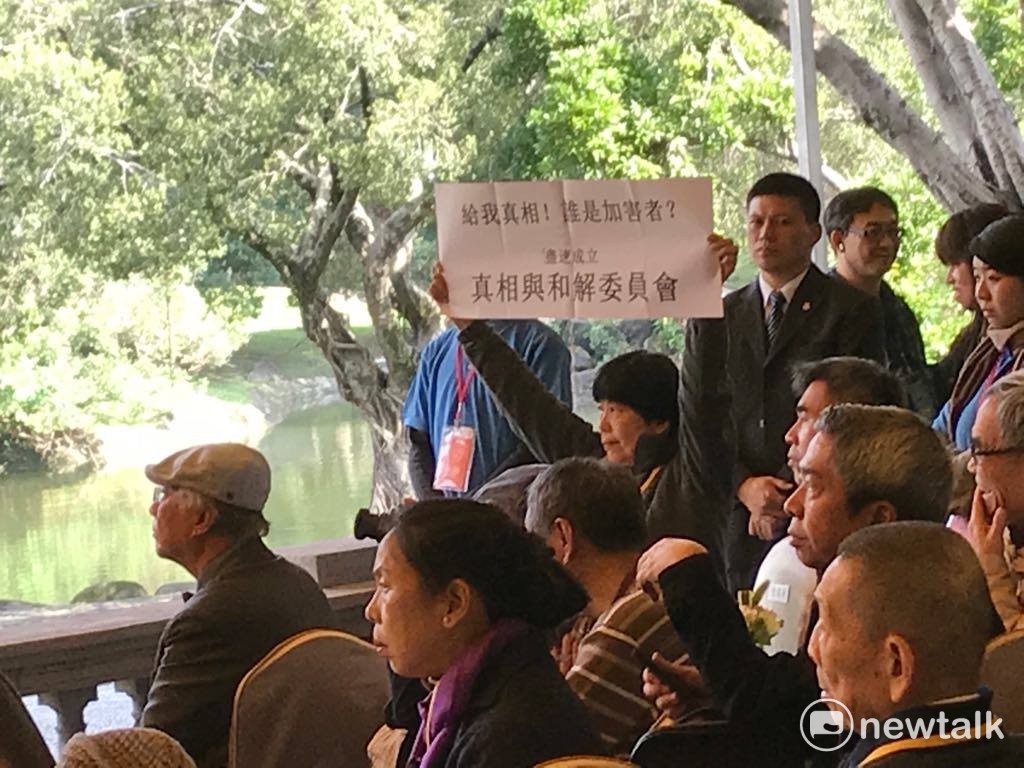 總統蔡英文致詞時，東吳大學哲學系教授陳瑤華高舉「給我真相！誰是加害者？儘速成立真相與和解委員會」標語。 圖：周煊惠 / 攝