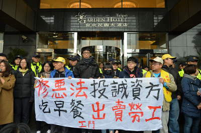 行政院長賴清德12日與工商團體領袖舉行「中華民國工
商協進會工商早餐會」，勞工團體在會場門口高舉布條
、喊著口號表達對勞基法修法的立場。 圖：中央社