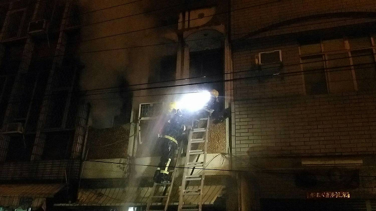 屏東縣新園鄉住宅火警，起火樓層疑為3樓建築物的頂樓鐵皮加蓋，警消架長梯冒險進行救援。 圖：屏東縣政府消防局提供