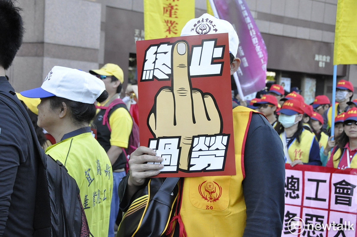 民眾手拿「終止過勞」標語參加遊行。 圖： 黃韋銓/攝