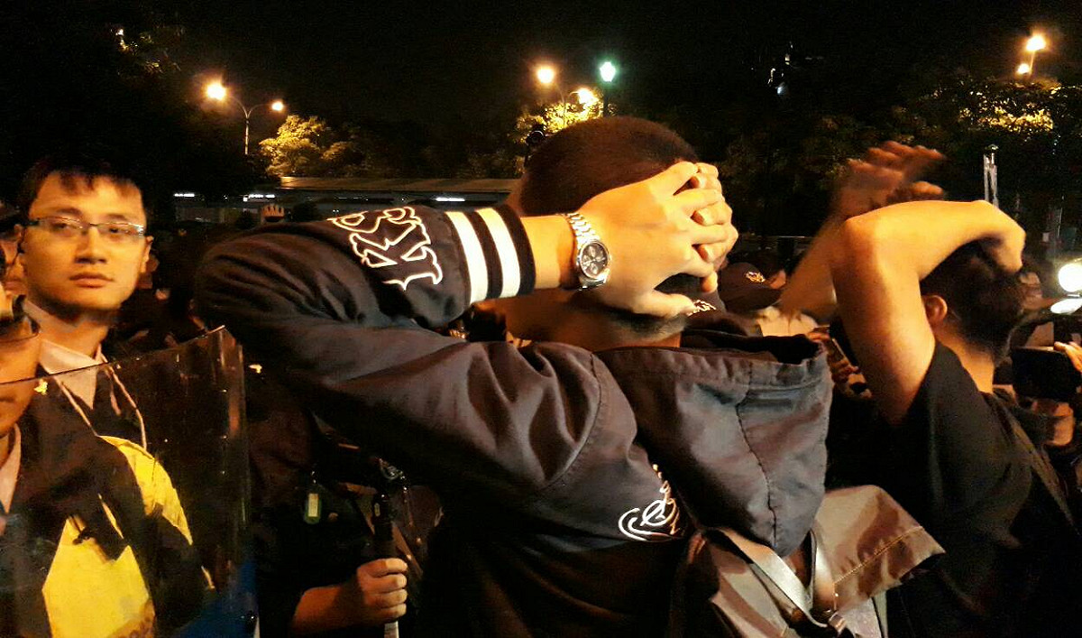 警察包圍，有人拿掉一名警察帽子，該名警察失控扭打那名男子。 圖：陳香蘭/攝