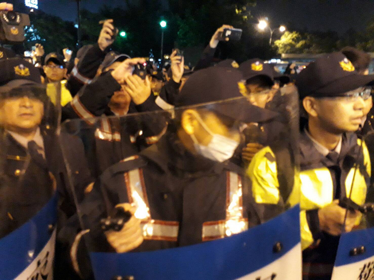 警察包圍，有人拿掉一名警察帽子，該名警察失控扭打那名男子。 圖：陳香蘭/攝