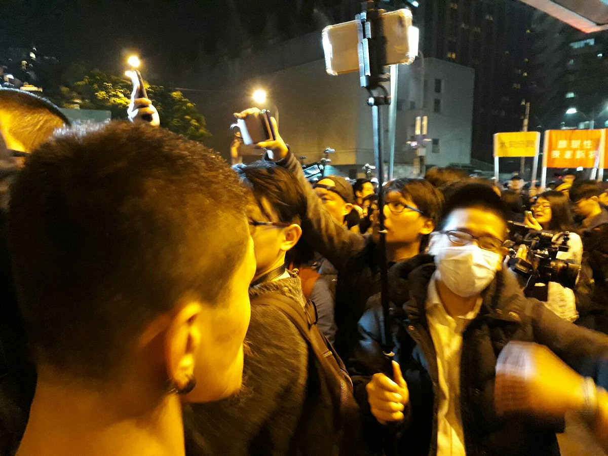 警察包圍，有人拿掉一名警察帽子，該名警察失控扭打那名男子。 圖：陳香蘭/攝
