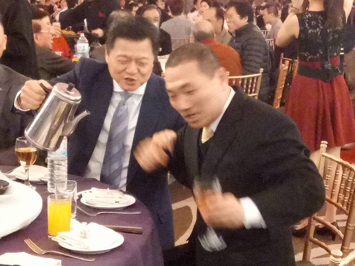 周錫瑋、侯友宜今天中午餐加喜宴，比鄰而坐，周要幫侯斟茶，侯一手挪杯子、一手攔阻茶壼，婉拒周的服務。 圖 :  讀者提供