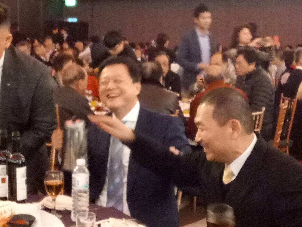 周錫瑋、侯友宜今天中午餐加喜宴，比鄰而坐，周要幫侯斟茶，侯一手挪杯子、一手攔阻茶壼，婉拒周的服務。 圖 :  讀者提供