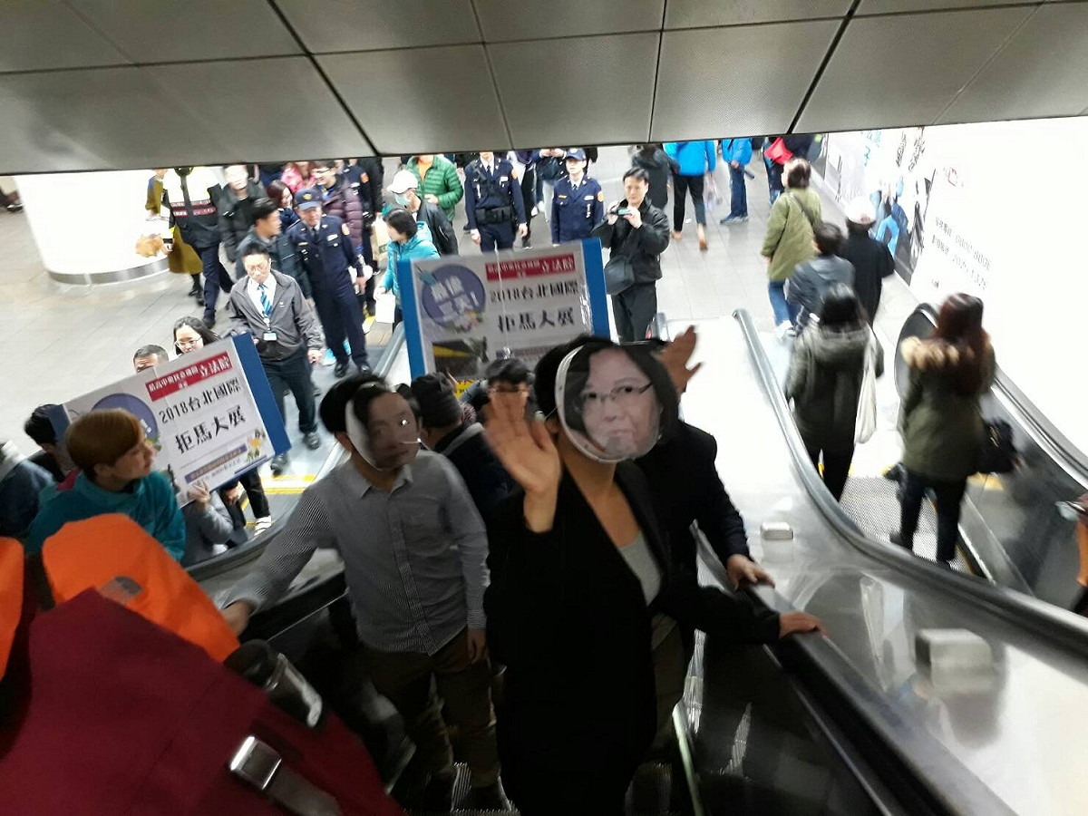 勞團今（9）日前往北車突擊，他們沿著台北車站地下街走上演行動劇，扮演「蔡英文」與「賴清德」面具進行諷刺。 圖：陳香蘭/攝