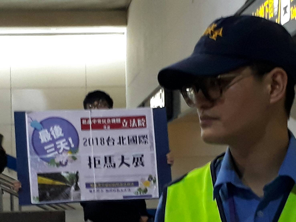 勞團人士9日在台北車站大廳高舉「2018台北國際拒馬大展」看板。 圖：陳香蘭/攝