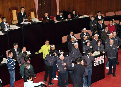 立法院臨時會院會9日處理勞動基準法部分條文修正草案，民進黨團提案延長開會時間直至完成三讀。圖為稍早表決勞動基準法第24條時，國民黨立委頭綁白布條，擺上大海報，不斷發言杯葛。 圖 : 中央社