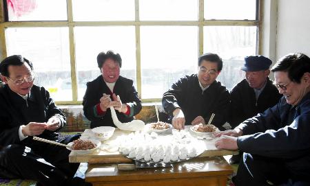 2004年1月20日至21日，中共中央總書記、國家主席胡錦濤（中）在河北省張家口市考察工作。這是胡錦濤等在張北縣油簍溝鄉喜順溝村看望干部群眾時，與村民呂佔林一家一起包餃子。 圖：新華網