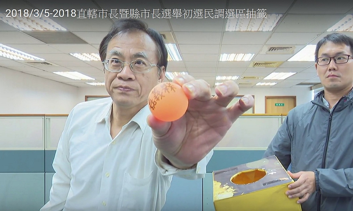 民進黨民調中心副主任5日抽籤後手舉嘉義縣的乒乓球。 圖：民進黨youtube直播網站