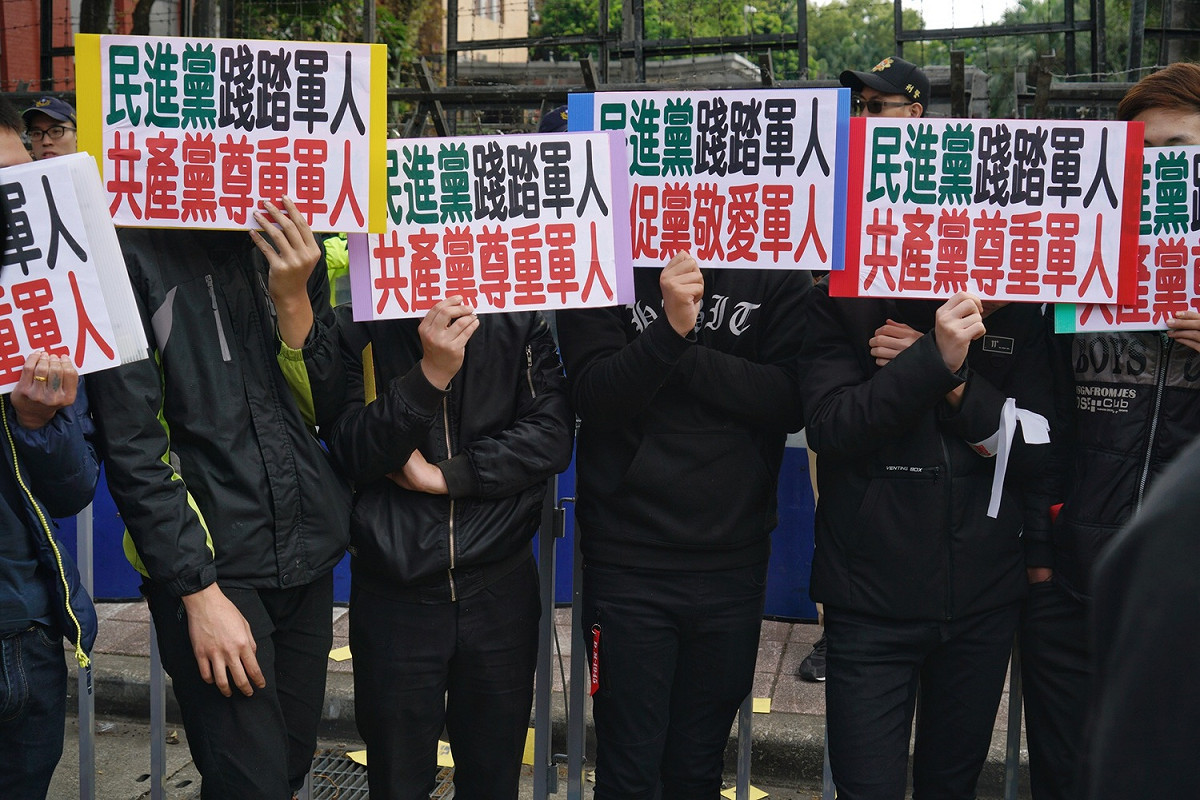 統促黨成員拿著牌子避開媒體拍攝。 圖：張良一/攝