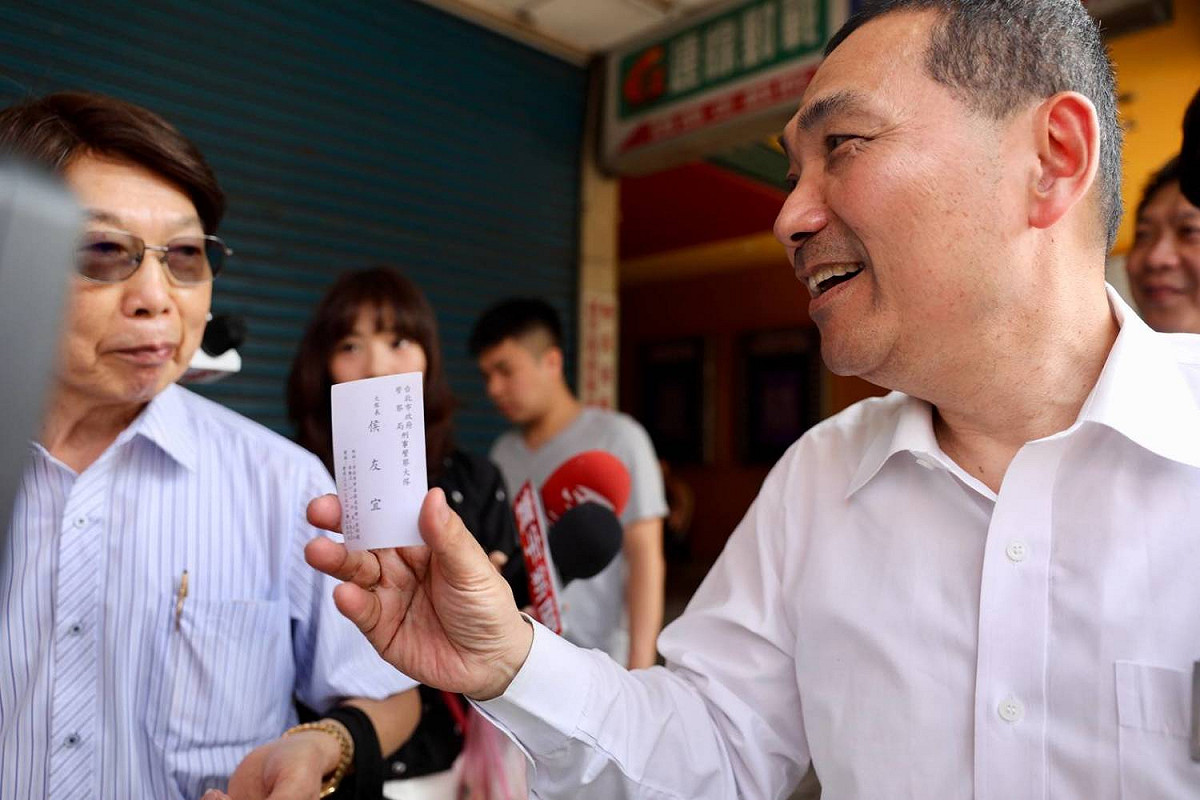 侯友宜拜票遇到鐵粉拿著他20年前擔任台北市刑大大隊長的名片要求簽名合照，看到自己的舊名片被保存的這麼好，侯友宜相當感動。 圖: 侯友宜競選辦公室/提供