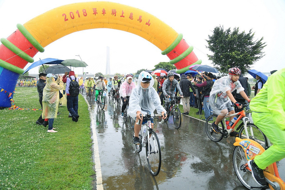 新北市八里龜馬山真慶宮今（15）天舉辦「2018單車騎上龜馬山」活動，選手門冒雨勇往直前。 圖/新北市政府提供