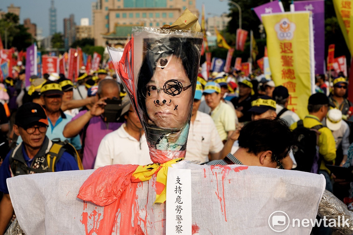 不滿公教警消退撫新制將於七月一日正式上路，軍公教警消團體將蔡英文的頭像做成稻草人上街遊行。 圖：張良一／攝