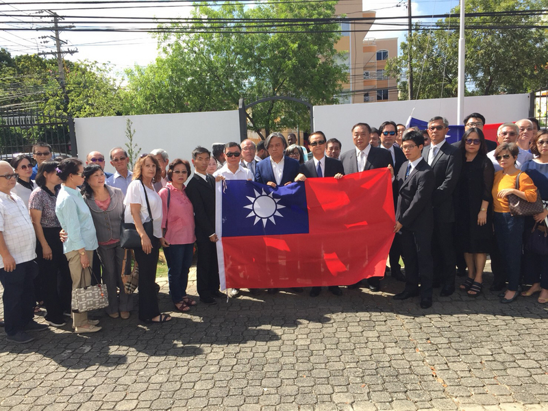 中華民國與多明尼加斷交後，駐多明尼加大使館於當地時間1日下午，舉行降旗典禮，使館人員與當地僑胞與降下的國旗合影。 圖：僑委會提供