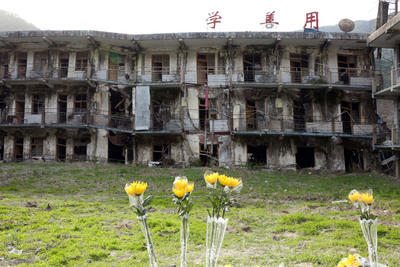 四川北川還保留2008年地震時破損的房屋。5月初，在北川職業中學遺址前，當年的師生結伴悼念遇難者，留下鮮花。 圖/中新社