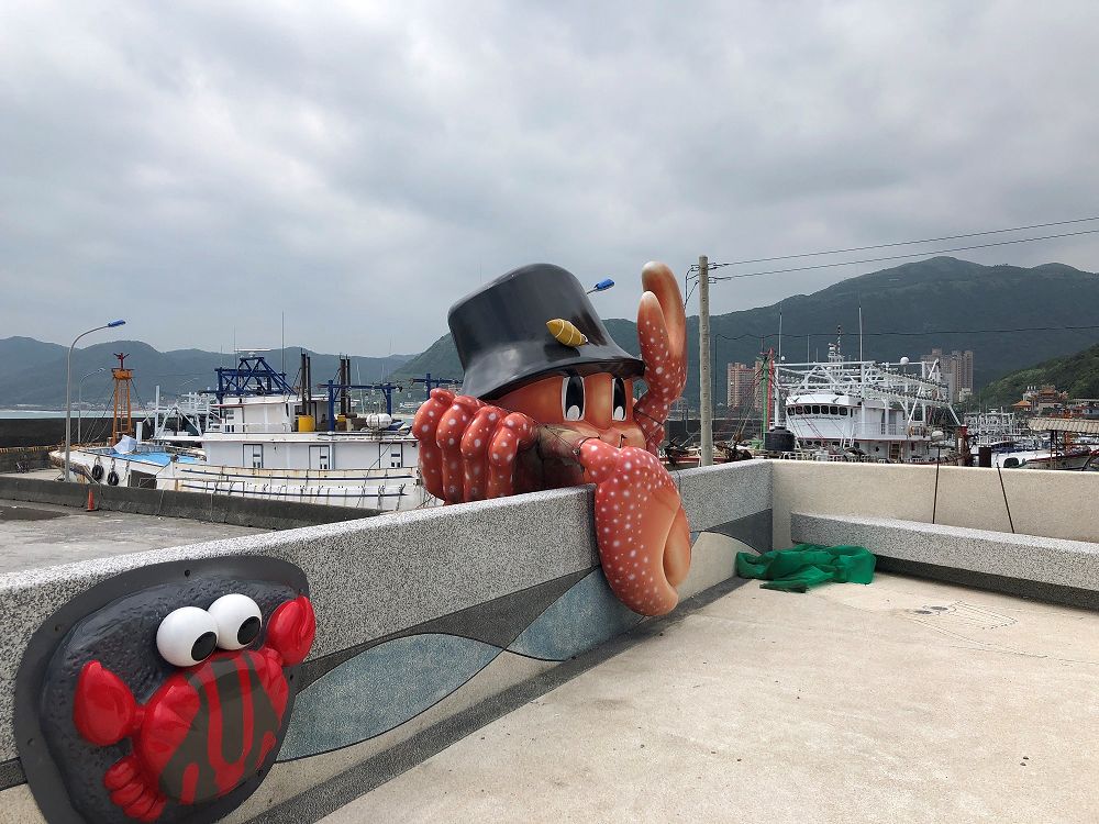北海岸的「龜吼漁夫市集」，有42家攤商，還有維納斯海岸還設有觀景平臺，可登高遠眺基隆嶼美景，鄰近還有超Q螃蟹公仔的「萬里蟹主題公園」、野柳地質公園，帶媽咪到北海岸的龜吼漁港吹吹海風、看美景吧！ 圖：新北市政府提供