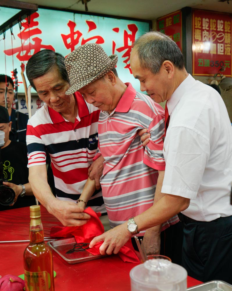 亞洲蛇肉店的董事長郭來貢（中）和殺蛇師傅洪丁福（左）共同將一把使用數十載，殺蛇無數的剪刀封刀。 圖：張良一/攝