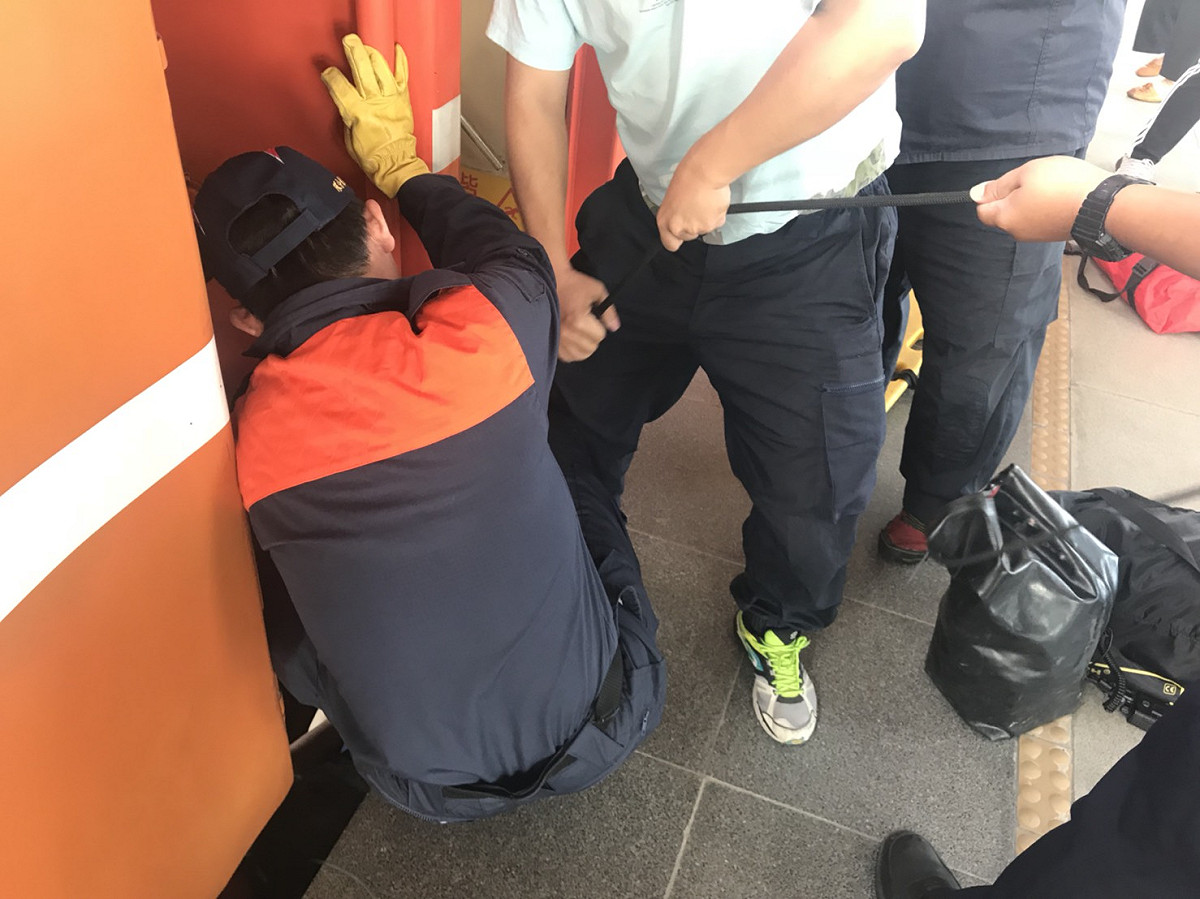 台鐵701次從新左營開往台東的莒光號，上午在屏東站準備開車時，有一名女性乘客不顧列車已開始移動，想強行上車，卻不慎在車門口滑倒，卡在月台與車廂間。 圖：屏東消防局/提供