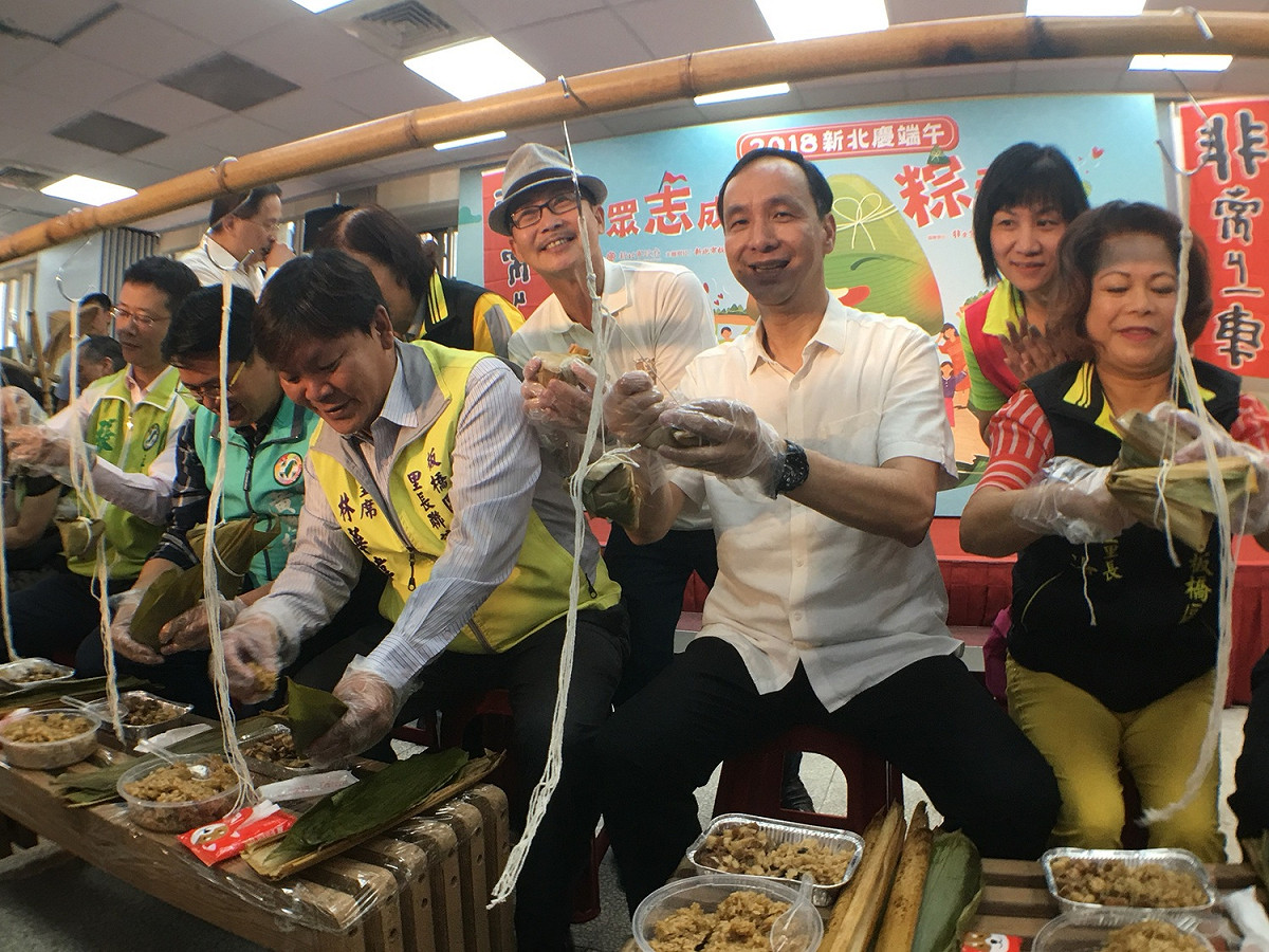 朱立倫與多位民進黨籍立委、議員及里長，一起包愛心粽。                                                
 圖：板橋區公所提供