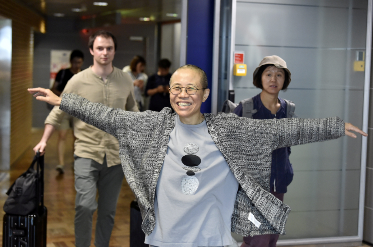 劉霞在台北時間10日晚間11時抵達特格爾機場後，隨即搭乘黑色廂形車離去，未和數十名在機場等候的記者及手持「歡迎劉霞」標語的維權人士交談。圖為劉霞下機後，呼吸到新鮮自由的空氣，不禁攤開雙手，露出久違的開懷笑容。 圖：達志影像/路透社