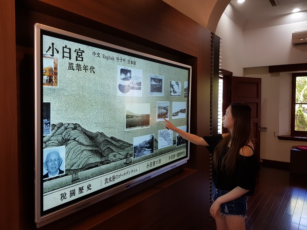 淡水古蹟博物館今年(107)將內部展區升級，運用互動多媒體及藝術畫將科技與美學導入歷史場域中，以超大觸控式螢幕呈現海關與小白宮從古到今的照片。 圖：淡水古蹟博物館提供