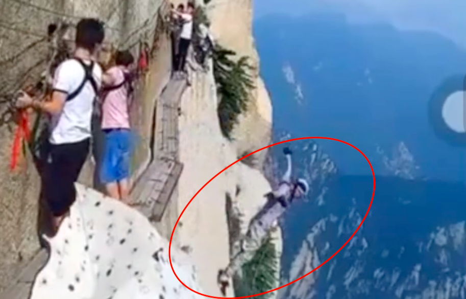 還在木棧道上慢慢行走的旅客被跳下的灰衣男子嚇呆。 圖：翻攝騰訊視頻
