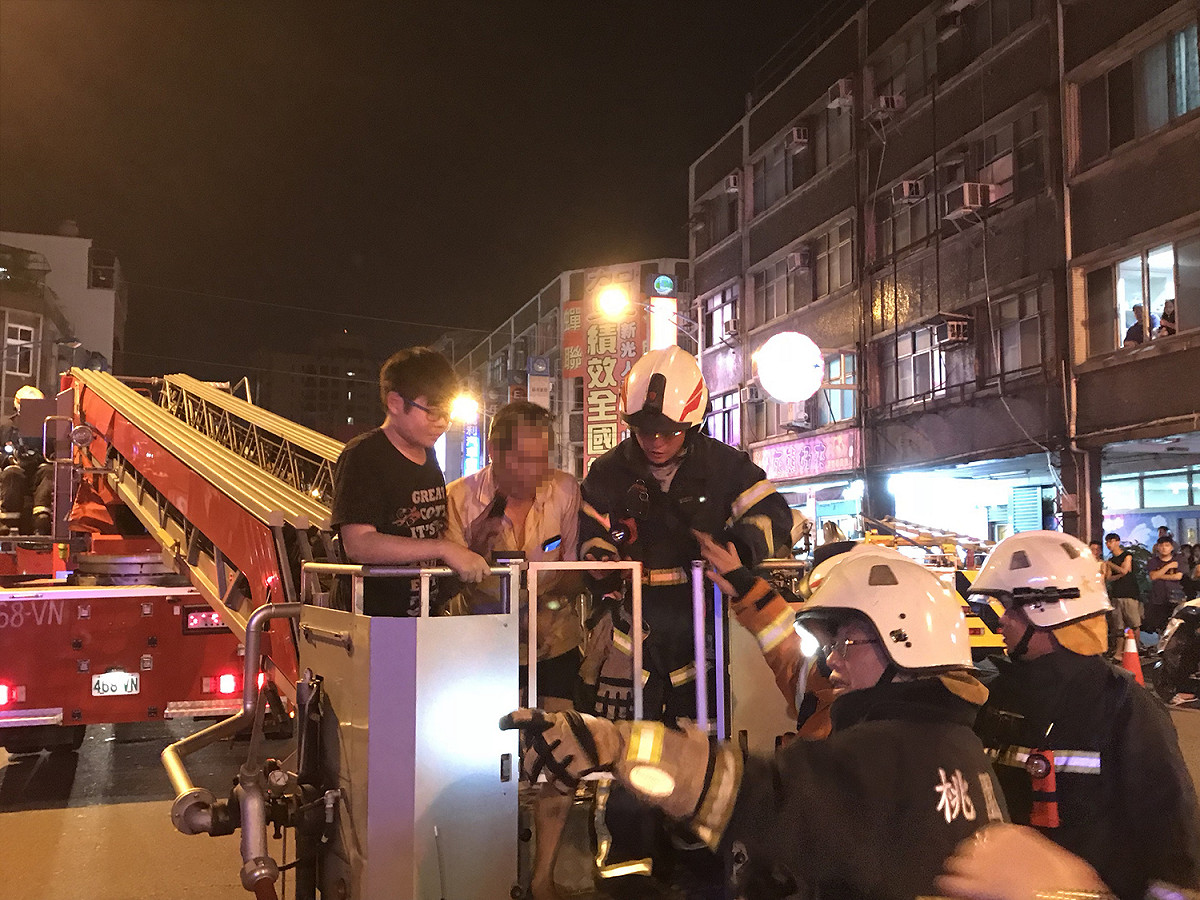 劉姓屋主跳在隔壁頂樓呼救，消防局以雲梯車順利救出。 圖:桃園市政府消防局/提供