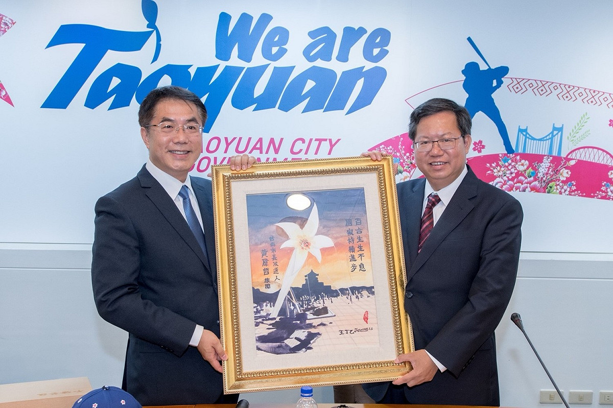 台南市長參選人黃偉哲（左）致贈桃園市長鄭文燦（右）一幅野百合畫作。 圖:桃園市政府/提供