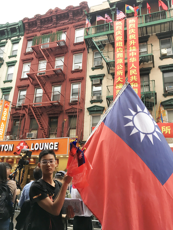 紐約僑團遡源公所今天改掛五星旗，一名中國大陸青年不畏風雨，高舉中華民國國旗抗議。 圖／中央社