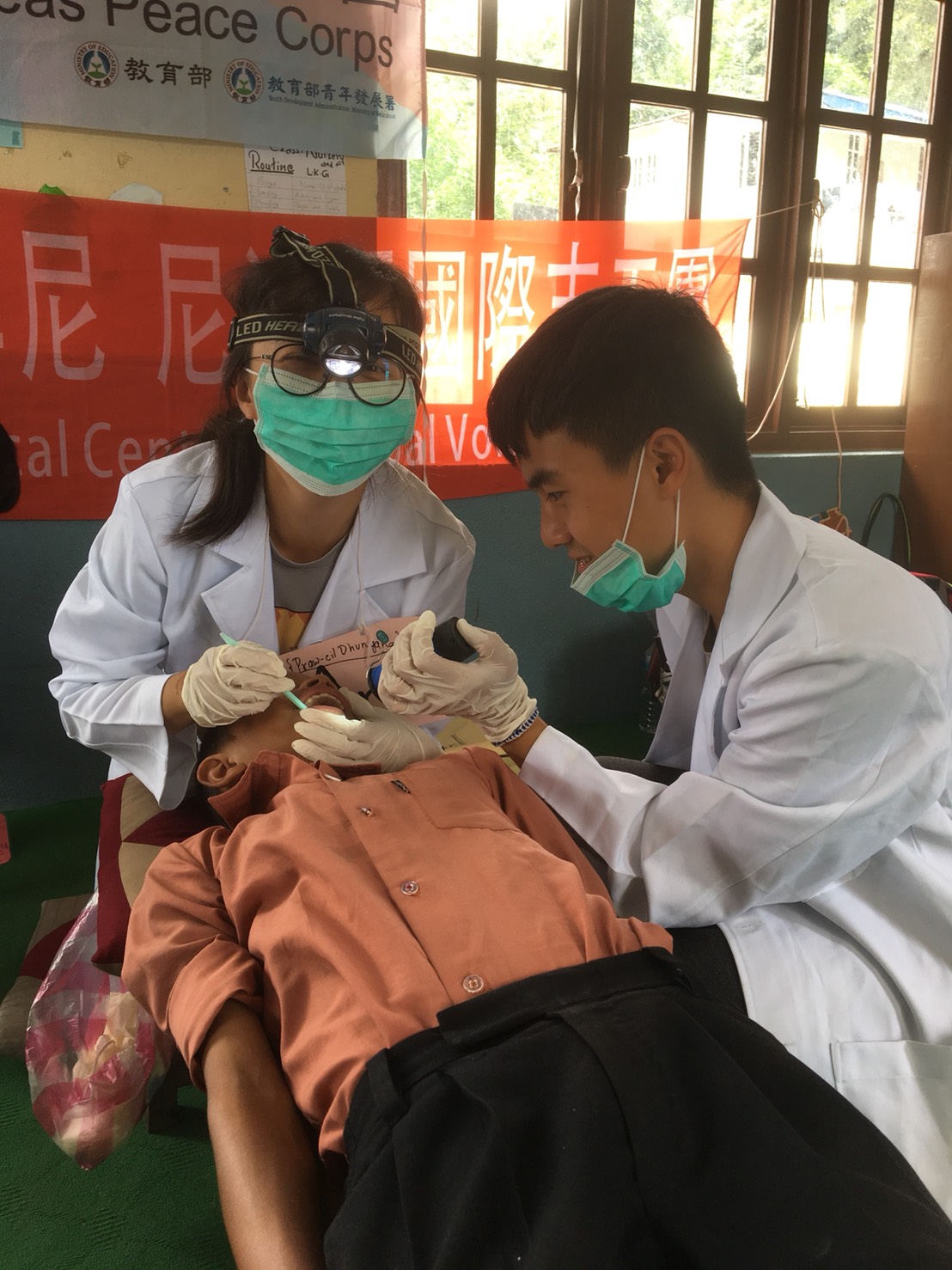 志工學生為孩童檢查牙齒。 圖：尼泊爾靈鷲山慈善基金會/提供