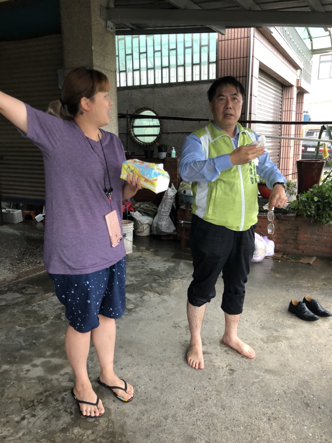 黃偉哲勘災時見一輛計程車因誤入積水區而拋錨，立即捲起褲管，涉水協助司機將計程車推回地勢較高處。 圖：黃偉哲競選總部/提供