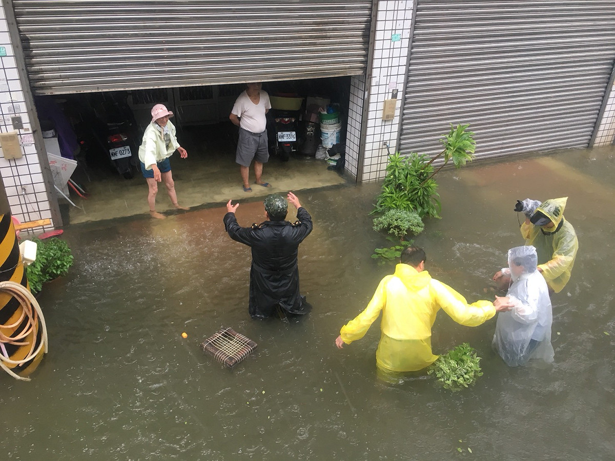 嘉義縣淹水嚴重，縣長張花冠（著白色雨衣者）關心受災民眾。 圖：嘉義縣政府/提供