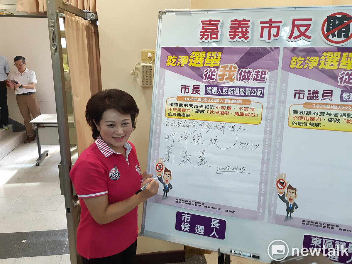 無黨籍嘉義市長候選人蕭淑麗今天前往嘉義市選委會登記參選嘉義市長，在反賄選公約看板上簽名。 圖：蔡坤龍/攝