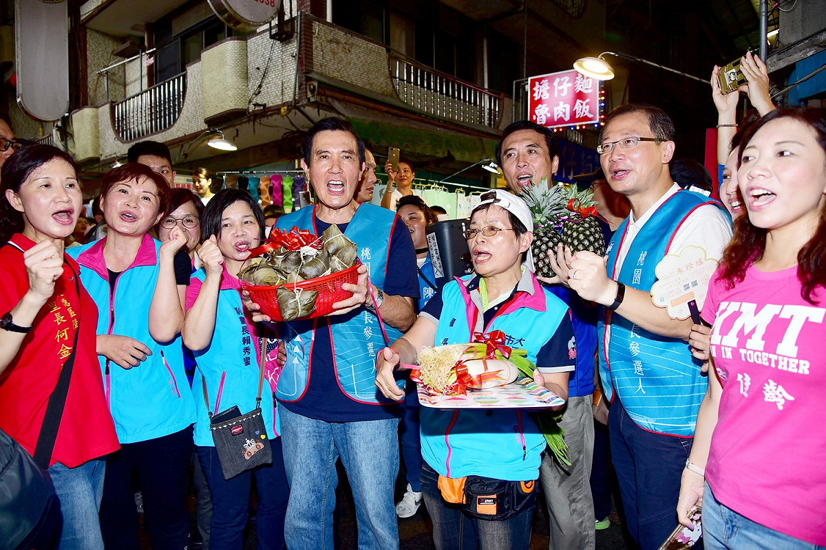 大湳市場店家送上鳳梨、肉粽、白蘿蔔及蒜，和馬英九、市長參選人陳學聖、立委吳志揚及市議員參選人合影、高喊「凍蒜」。  圖：陳學聖競選辦公室／提供