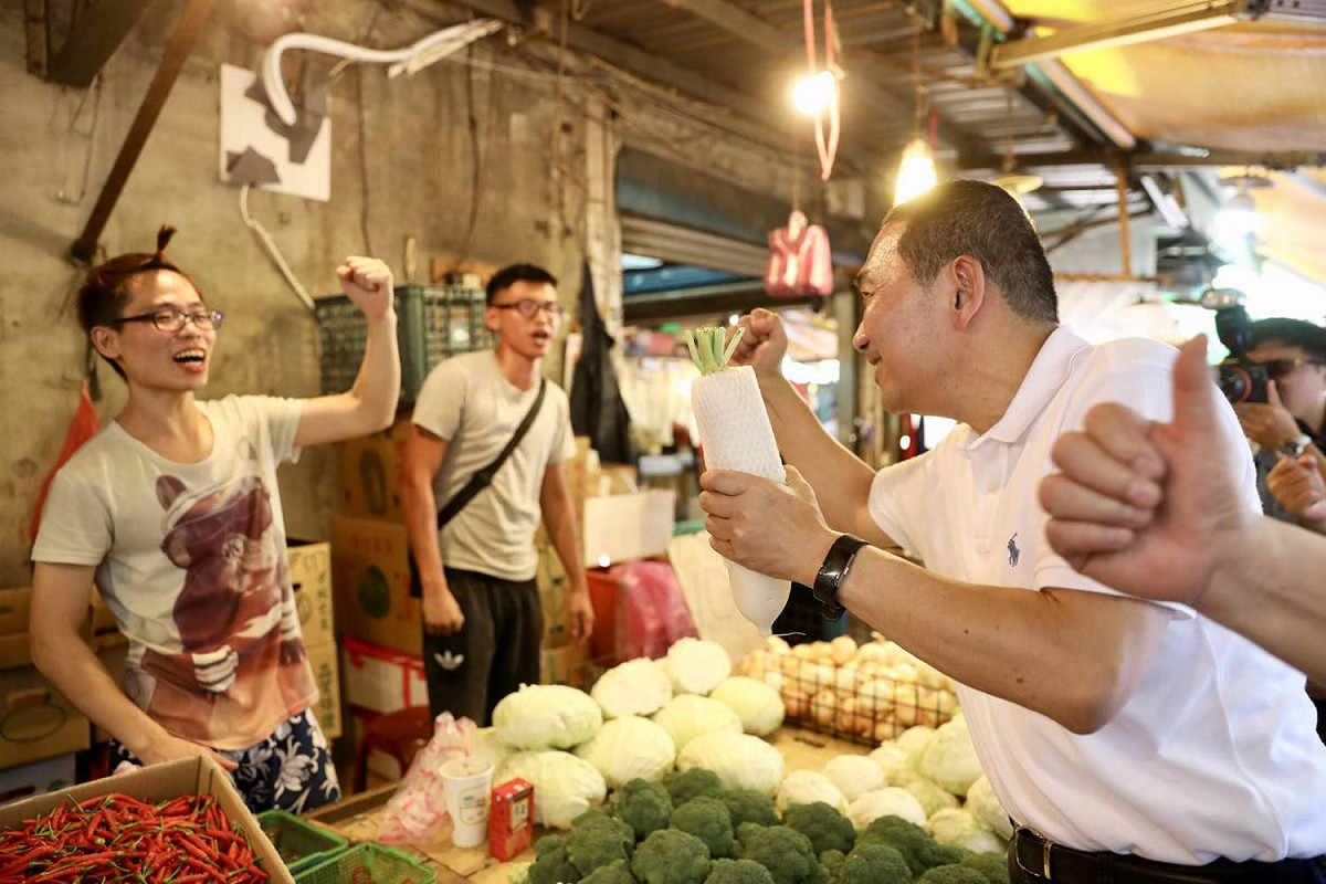 侯友宜到新莊區宏泰市場掃街拜票，受到支持民眾和攤商熱情歡迎，攤商還送上菜頭象徵好彩頭。 圖：侯友宜競選辦公室／提供