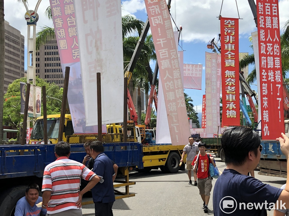 上百輛大貨車、大卡車停在中山南路與忠孝西路口，所有吊車將標語懸掛數公尺高，並屢次鳴笛抗議。 圖：謝莉慧/攝
