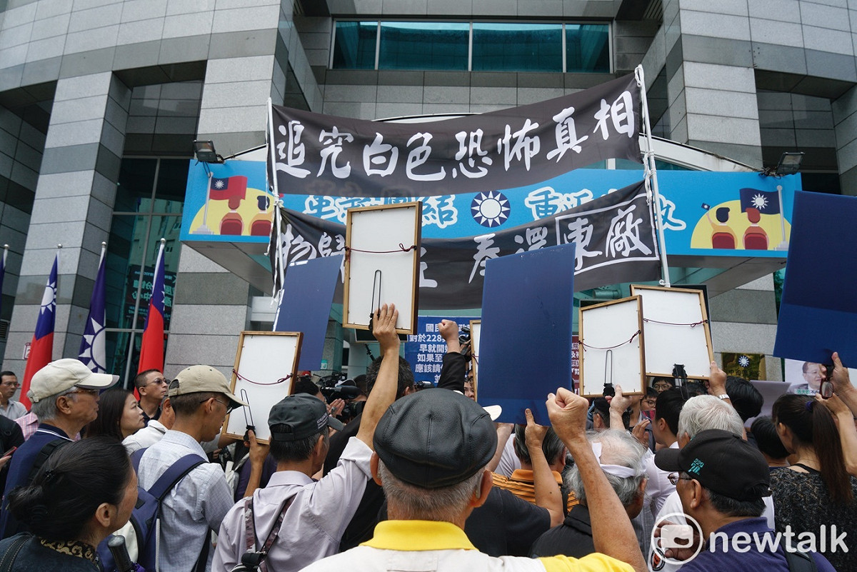 政治受難者團體拿著政治受難者的遺像在國民黨中央前，抗議國民黨藉著促轉會事件，無視歷史創傷、顛倒是非。 圖：張良一/攝