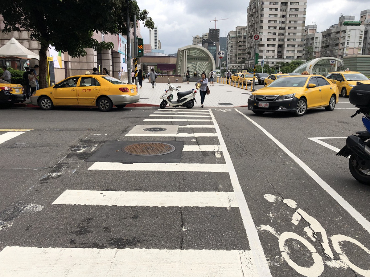 一輛警用巡邏機車大喇喇直接停放在斑馬線上，結果過馬路的民眾都必須繞到斑馬線兩邊來行走。 圖 : 民眾/提供
