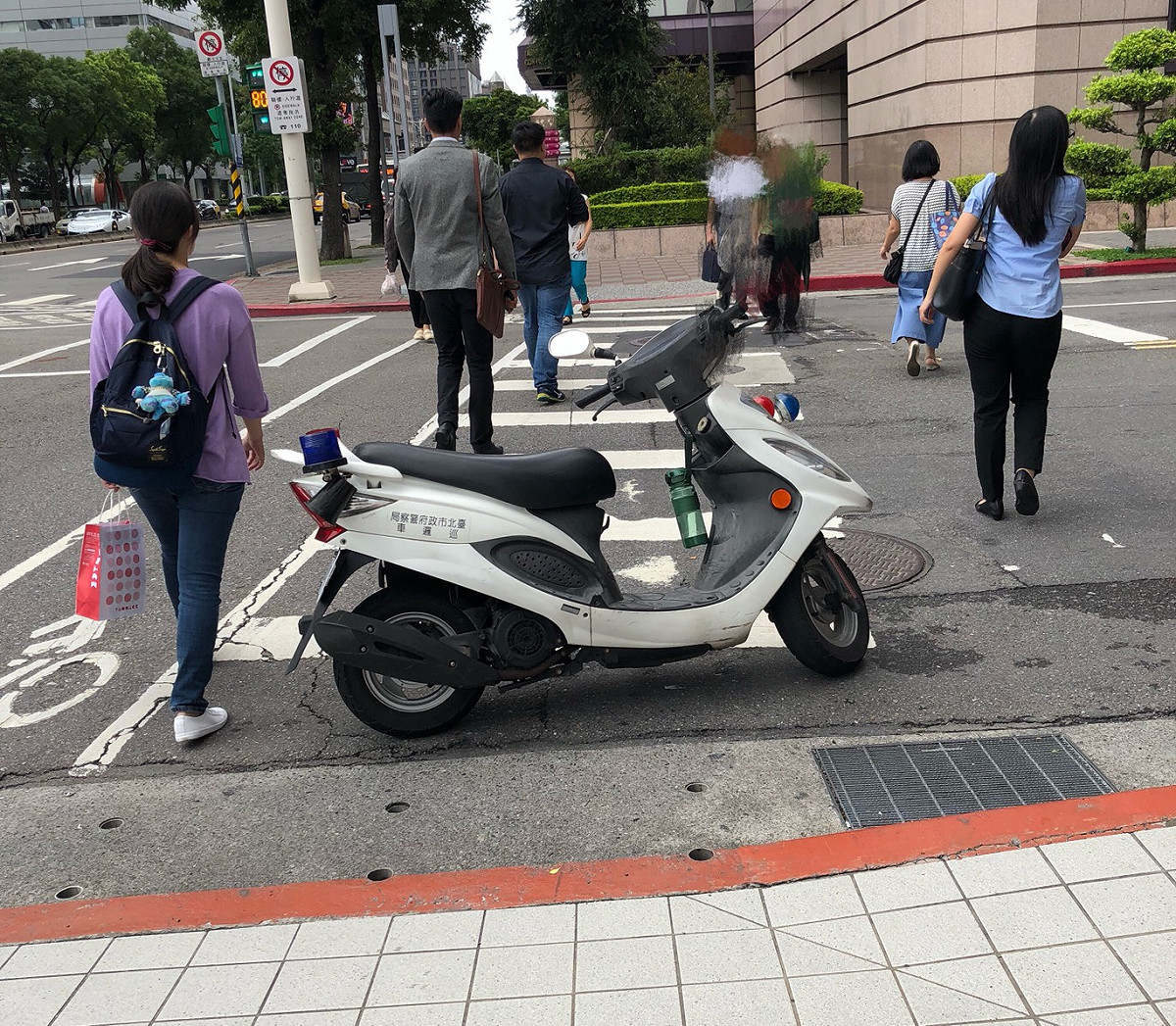 一輛警用巡邏機車大喇喇直接停放在斑馬線上，結果過馬路的民眾都必須繞到斑馬線兩邊來行走。 圖 : 民眾/提供