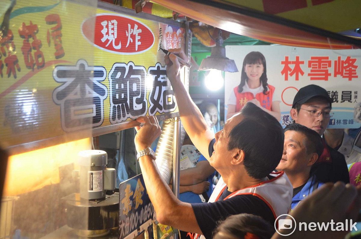 前總統馬英九5日晚間陪同國民黨嘉義市長候選人黃敏惠到傳統文化路夜市掃街拜票，在攤車上簽名。 圖：蔡坤龍/攝