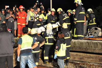 台鐵6432車次普悠瑪列車21日下午行經宜蘭蘇澳新馬站時發生出軌翻覆事故，大批警消馳援搜救，晚間合力將不幸罹難的民眾遺體搬出車廂。 圖：中央社