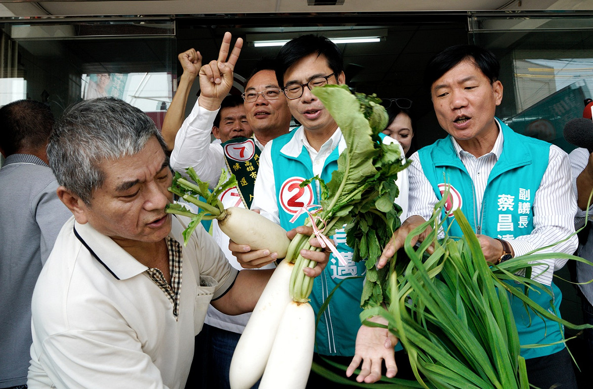 支持者送給陳其邁的菜頭不小心滑掉了，讓陳其邁露出驚訝的表情。 圖：張良一/攝