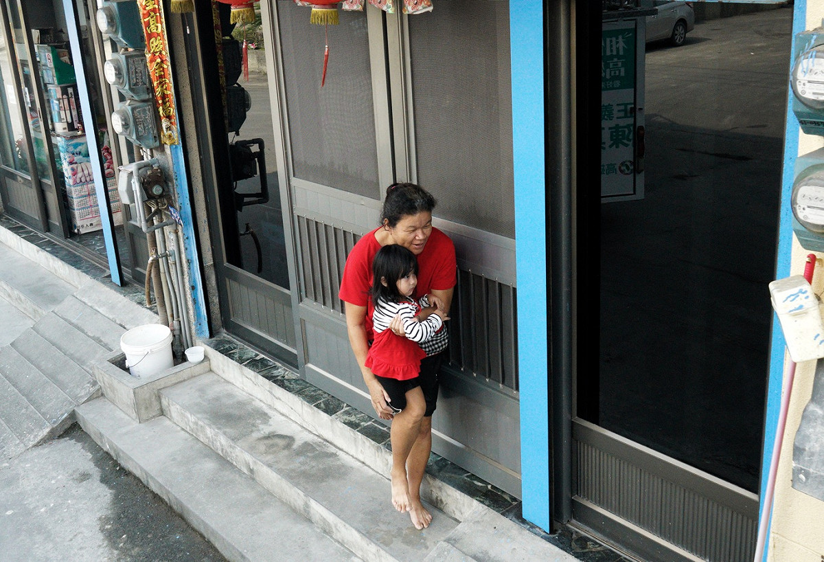 一位阿嬤急忙將孫女抱起免的被鞭炮聲嚇到。 圖：張良一/攝