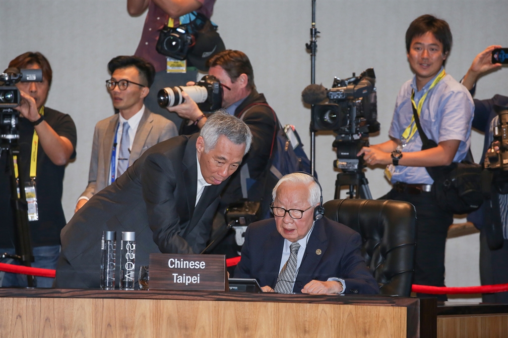 亞太經合會（APEC）領袖閉門會議18日舉行，APEC領袖代表張忠謀在會場裡坐在新加坡總理李顯龍、泰國總理帕拉育（Prayut Chan-O-Cha）中間，圖為李顯龍協助張忠謀操作現場設備。 圖 : 中華台北代表團/提供