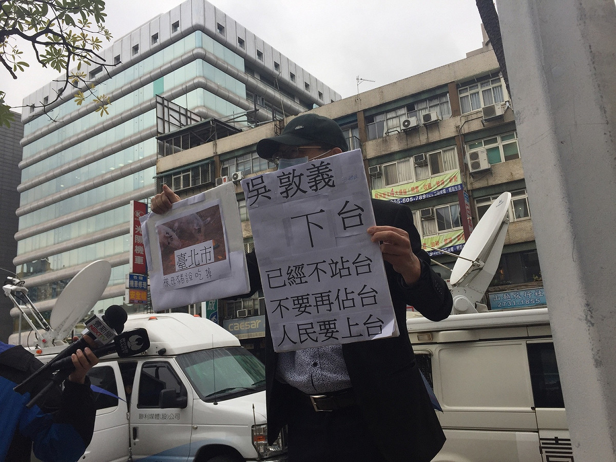 中常會召開前，有民眾手持「吳敦義下台、韓國瑜上台」告示牌抗議。 圖：趙婉淳／攝