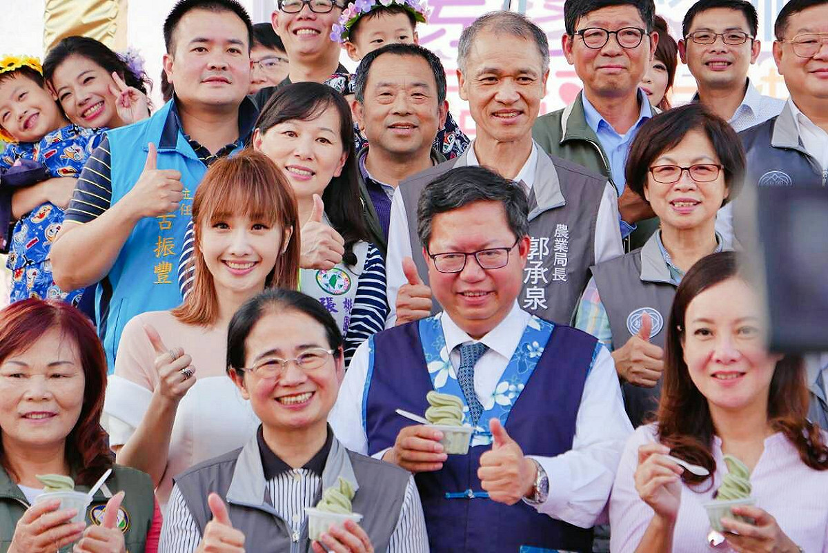 桃園市長鄭文燦與歌手朱俐靜 (二排左)，一起邀請現場民眾共享楊梅限定仙草霜淇淋。 圖：桃園市政府/提供