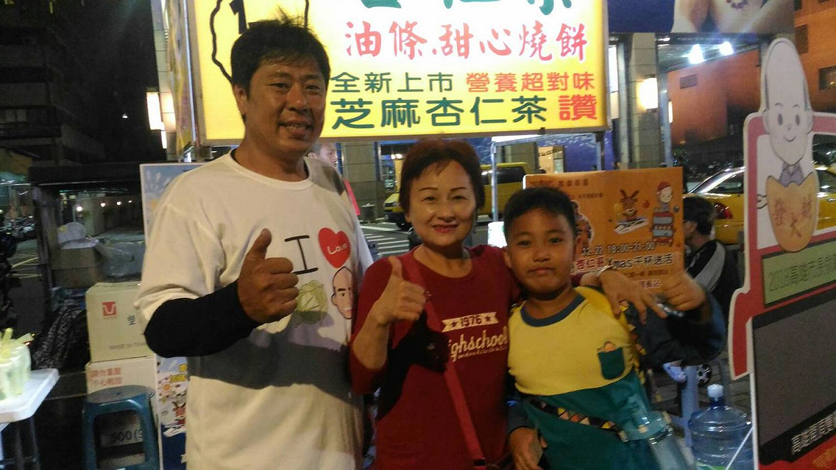 一對祖孫和杏仁哥在臨時攤位前合照 圖：孫家銘／攝